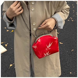 Détail du sac rouge à motif bambou avec poignée métallique et chaîne rétro
