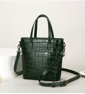 Close-up of crocodile pattern texture on dark green faux leather bucket bag