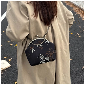 Gros plan d'un sac vintage à fermoir avec motif bambou et poignées anneaux en métal