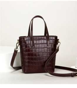 Close-up of deep burgundy crocodile pattern bucket bag with fine stitching and metal hooks