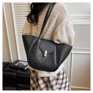 Detail of black woven tote bag with metallic clasp and folded side structure