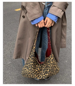 Close-up of leopard print tote bag with dark red lining and metallic eyelet detail
