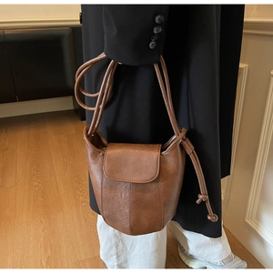 Brown vintage leather bucket bag with drawstring strap shown on model in side view