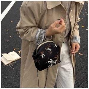 Détail d'un sac vintage noir avec broderie de feuilles de bambou et chaîne en métal