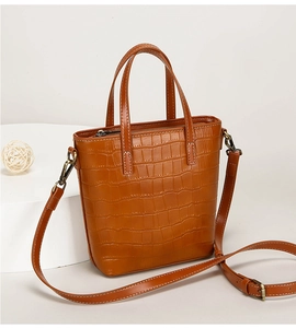 Close-up of brown crocodile pattern bucket bag with round handles and adjustable strap