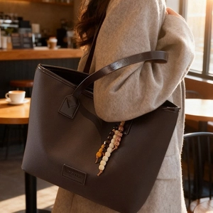 Brown leather tote bag with colorful beaded charms for women in a cafe setting