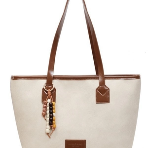 Classic cream canvas tote bag with brown leather handles and ethnic bead charm detail