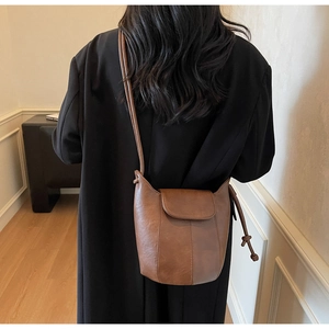 Detailed back view of model wearing a vintage brown matte leather bucket bag with drawstring
