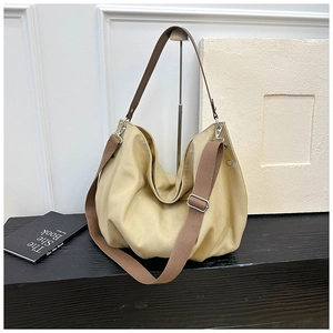 Detailed view of yellow canvas tote bag with brown adjustable shoulder straps and silver hooks