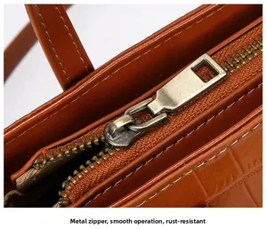 Close-up of retro brass zipper and crocodile embossed leather on brown bucket bag
