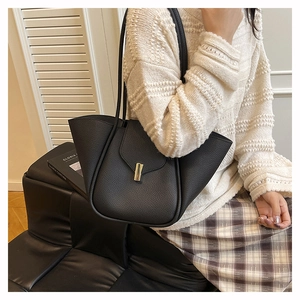 Detailed view of black litchi pattern leather shoulder bag with gold metal clasp and wide gussets