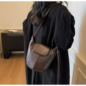 Detail view of deep brown bucket bag with vintage leather texture and vertical stitching