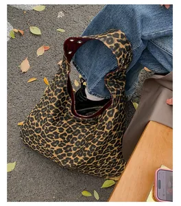 Detail of leopard print hobo tote bag with red lining and metal eyelet straps