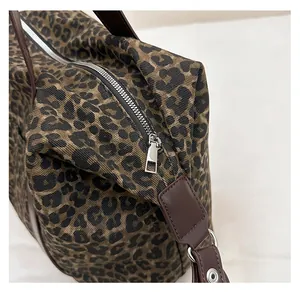 Close-up of smooth silver metal zipper and reinforced leather handles on leopard tote bag