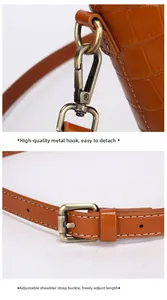Detail of crocodile embossed bucket bag featuring vintage hardware hooks and adjustable strap