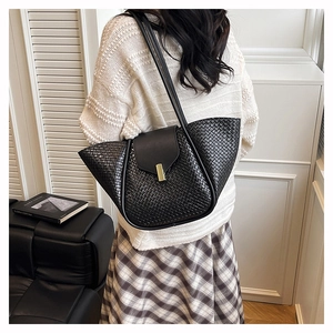 Macro shot of large black woven shoulder bag featuring a premium gold metal lock buckle