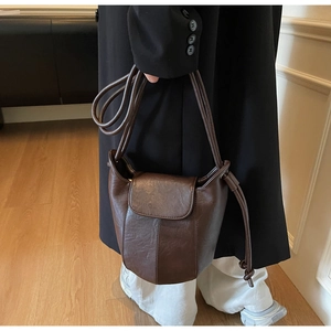 Detail of dark brown leather bucket bag with flap closure and dual round handles