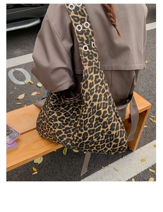 Outdoor shot of leopard print hobo bag with eyelet strap details on a trench coat