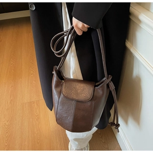 Detail of dark brown bucket bag showing premium leather texture and knotted strap design