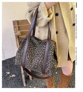 Outdoor shot of a leopard print tote bag with brown leather handles and a long shoulder strap