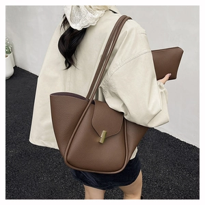 Detail of dark brown lychee leather tote bag and pouch set on a model shoulder