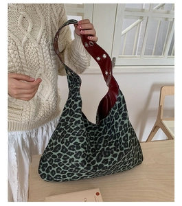 Detail of teal leopard print tote bag with dark red lining and silver eyelet strap