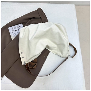 Detail of off-white oversized canvas tote bag with brown leather straps and metal hardware