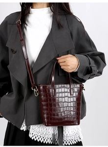 Close-up of deep burgundy crocodile embossed leather bucket bag with dual top handles