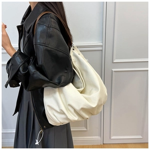 Detail of cream canvas hobo bag with brown leather strap and silver metal eyelets