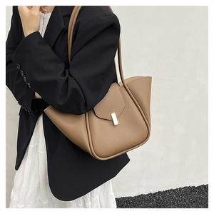 Detail of caramel lychee grain leather tote bag with wing design and gold buckle