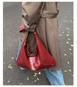 Detail of red glossy tote bag with leopard print lining worn with a khaki trench coat