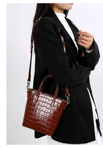 Detail of dark brown crocodile embossed tote bag with adjustable strap on a model