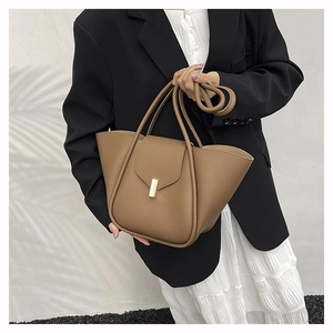 Brown lychee grain leather tote bag with gold metal clasp on a stylish female model