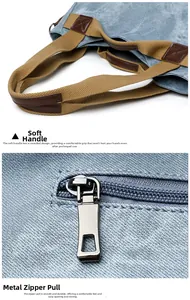Detail of blue canvas bag featuring brown webbing handles and high-quality metal zippers