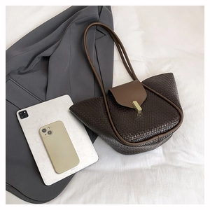 Detail of brown woven leather tote bag with gold metal buckle on white fabric