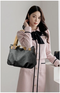 Close-up of black crossbody bag with bright yellow fabric handles and premium leather texture