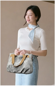 Close-up of casual grey canvas shoulder bag with vintage texture and brown handles