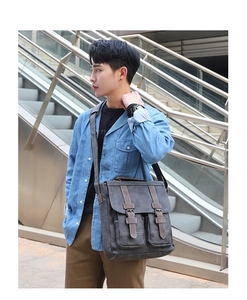 Detail of vintage charcoal messenger bag with brown leather straps and multi-pocket structure