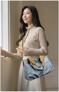 Detail of light blue canvas crossbody bag with brown leather trim and adjustable strap