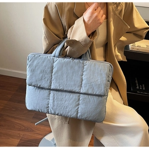 Detail of light blue quilted laptop bag showing puffy texture and soft fabric material