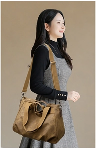 Brown canvas tote bag detail featuring wide shoulder strap and metal hook connectors