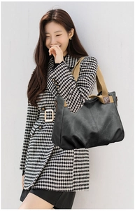 Detail of black leather tote bag featuring a contrasting khaki wide fabric shoulder strap