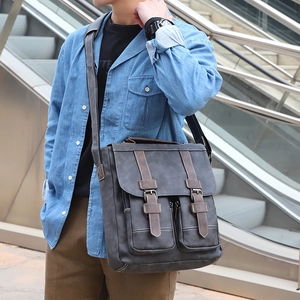 Close-up of a charcoal grey vintage canvas messenger bag worn by a model outdoors