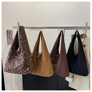 Detailed display of four leopard print and solid suede tote bags on a garment rack
