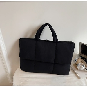 Close-up of black quilted laptop bag with double zippers and soft fabric texture