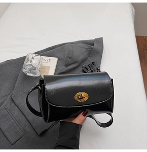 Detail of a black glossy square bag featuring a vintage golden oval twist lock closure