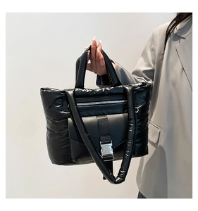 Détail du sac matelassé noir avec boucle en métal argenté et poche zippée pratique