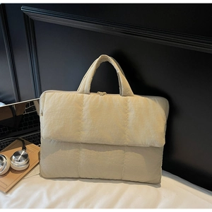 Detail of beige quilted laptop handbag with soft padded texture and top zipper closure