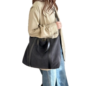 Classic large black canvas tote bag with leather handles shown from a front-facing perspective
