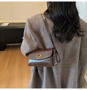 Brown vintage faux leather square bag with metal clasp worn over a gray wool coat